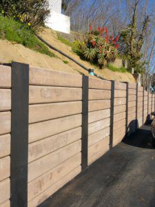 A wooden fence with a flower bed in the background.