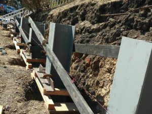 A concrete retaining wall is being built on a hillside.