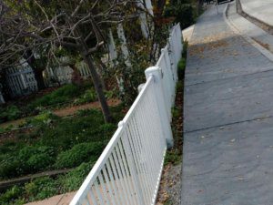 A white fence on the side of a sidewalk.