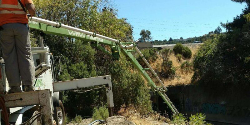 A man is working on a truck on a hillside.