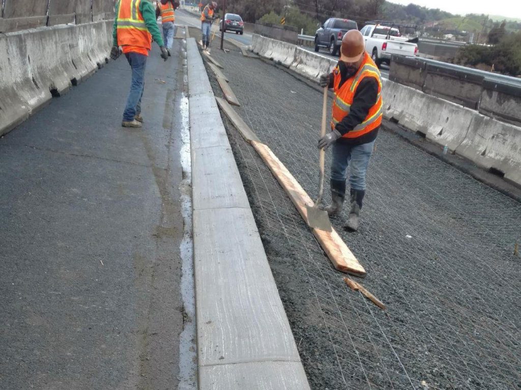 A group of workers are working on a concrete road.