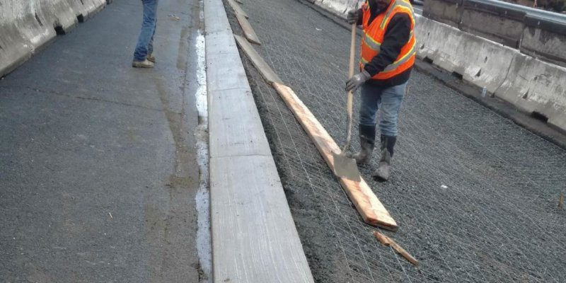 A group of workers are working on a concrete road.