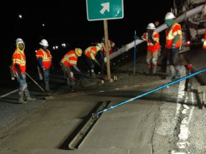 A group of construction workers working on a road at night.