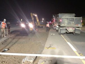 A construction crew is working on a road at night.