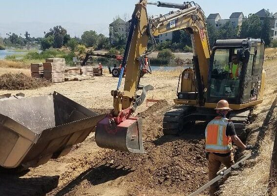 An excavator is working on a dirt road.