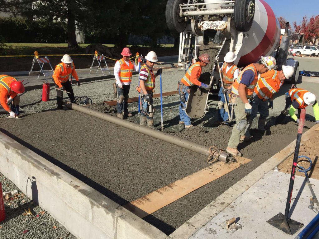 A group of construction workers working on a concrete slab.