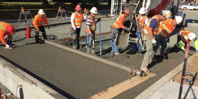 A group of construction workers working on a concrete slab.