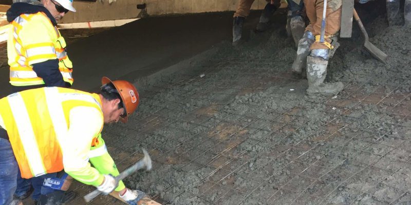 A group of construction workers are working on a concrete slab.