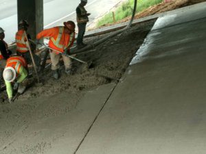 A group of construction workers working on a concrete slab.