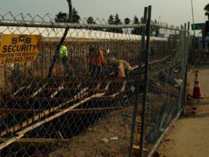 Workers are working on a construction site near a fence.