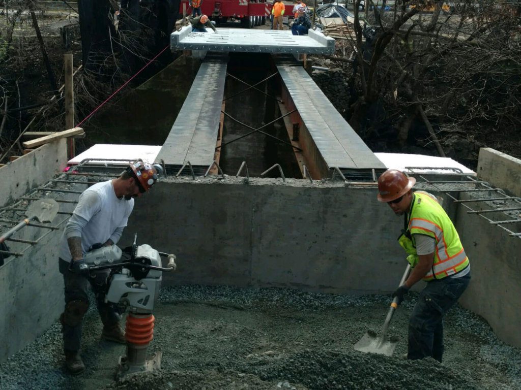 Two construction workers working on a bridge.