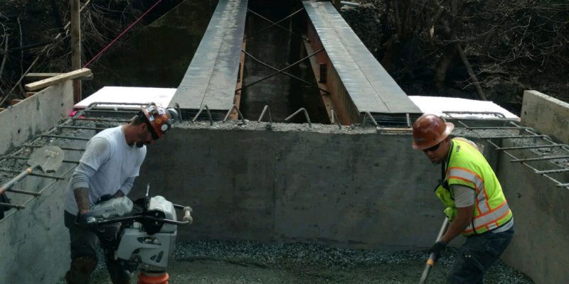 Two construction workers working on a bridge.
