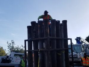 A worker is standing on top of a large pipe.