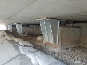 The underside of a bridge with sandbags under it.