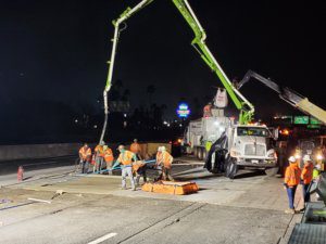 A group of workers are working on a road at night.