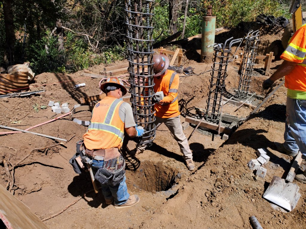 Two men working on a hole in the ground.
