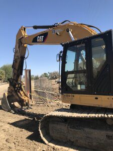 A yellow and black cat excavator on dirt ground