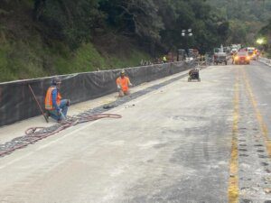 A group of construction workers working on the side of a road.