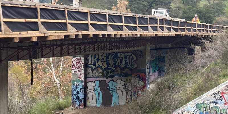 A bridge with graffiti on it and trees in the background.