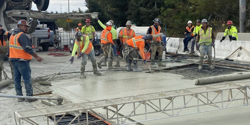 A group of construction workers standing on top of concrete.