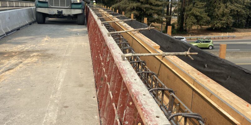 A truck driving down the road next to a bridge.